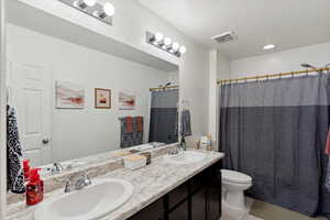 Full bath with toilet, double vanity, tile patterned floors, and a shower with curtain