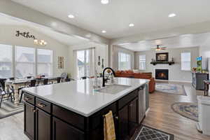 Kitchen with a large one basin sink, fireplace, natural light, light countertops, and vaulted ceiling