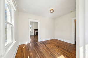 Empty room featuring wood-type flooring, a fireplace, and baseboards