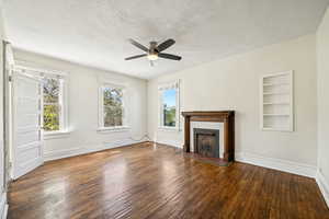 Unfurnished living room featuring a ceiling fan, healthy amount of natural light, wood-type flooring, and a textured ceiling