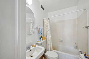Full bath featuring a sink, toilet, and shower / bathtub combination with curtain