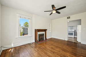 Unfurnished living room with hardwood / wood-style floors, ceiling fan, baseboards, and a brick fireplace