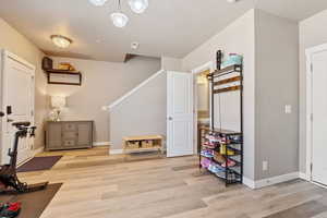 Exercise area with light wood-type flooring, baseboards, and a textured ceiling