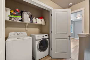 Washroom featuring washing machine and clothes dryer, light wood-style flooring, and a textured ceiling