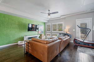 Living room featuring dark wood-type flooring, baseboards, a ceiling fan, and a textured ceiling