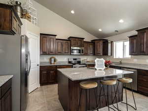Kitchen featuring stainless steel appliances, a sink, a center island, recessed lighting, and dark brown cabinetry