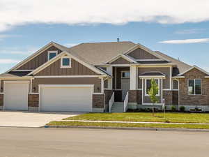 Craftsman house featuring driveway, board and batten siding, roof with shingles, an attached garage, and a front yard