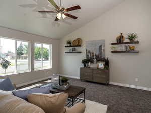 Living area featuring a ceiling fan, carpet, lofted ceiling, and baseboards