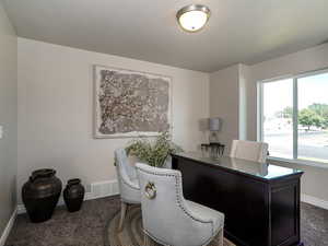 Office area featuring dark colored carpet and baseboards