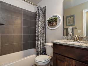 Full bath featuring toilet, vanity, and shower / bath combination with curtain