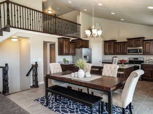 Dining area with high vaulted ceiling, a chandelier, light tile patterned flooring, recessed lighting, and baseboards