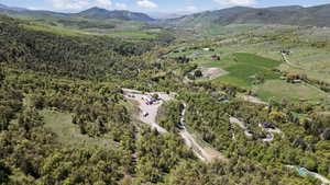 Aerial view of property and surrounding area featuring mountains and a forest