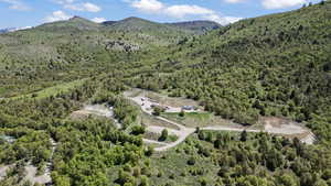 Aerial view of property and surrounding area featuring a forest and a mountain backdrop