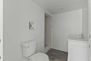 Bathroom with toilet, wood finished floors, vanity, and walk in shower