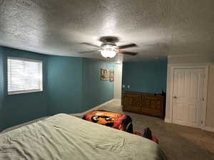 Carpeted bedroom with a textured ceiling and ceiling fan