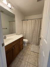 Full bathroom with vanity, a textured ceiling, light tile patterned flooring, and a shower with curtain
