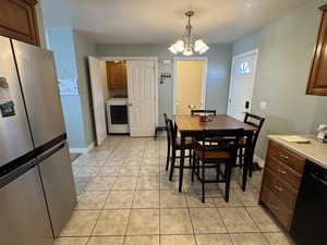 Dining space featuring washer / clothes dryer, light tile patterned floors, and a chandelier