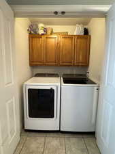 Washroom featuring cabinet space, independent washer and dryer, and light tile patterned floors