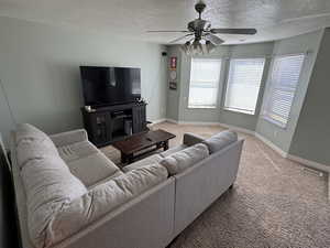 Living area with carpet flooring, a textured ceiling, and ceiling fan