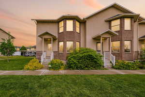 Townhome / multi-family property featuring brick siding, stucco siding, and a lawn