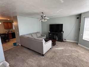 Living area with light carpet, a textured ceiling, and ceiling fan