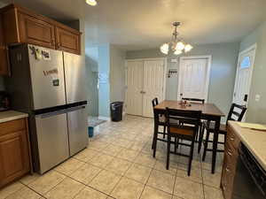 Kitchen with brown cabinetry, freestanding refrigerator, light countertops, and recessed lighting
