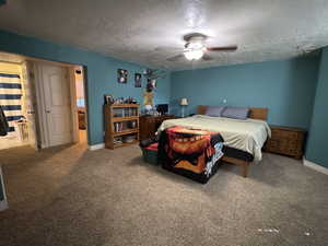 Carpeted bedroom with ceiling fan and a textured ceiling