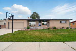View of front of property featuring a garage, brick siding, a front lawn, concrete driveway, and a chimney