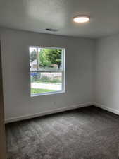 Empty room featuring dark carpet and baseboards