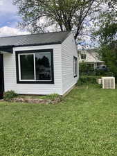 View of property exterior with metal roof and a yard