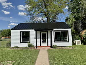 View of front of house featuring central air condition unit, metal roof, and a standing seam roof