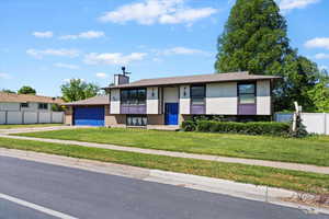 Split foyer home with driveway, a garage, and a chimney
