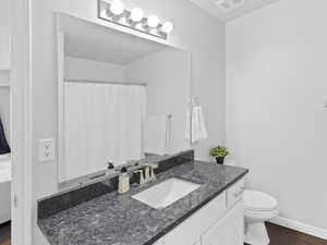 Full bathroom featuring vanity, toilet, baseboards, and wood finished floors