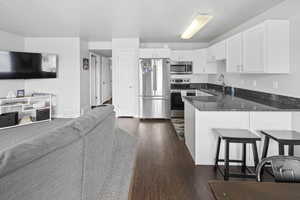 Kitchen with stainless steel appliances, open floor plan, a peninsula, and dark wood-style floors