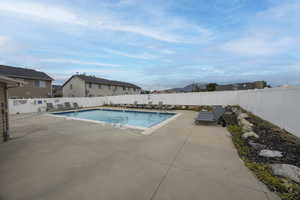 Community pool with a patio and a fenced backyard