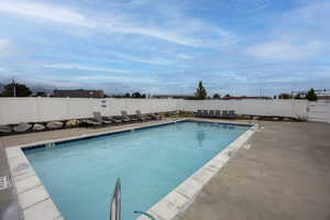 Community pool with a patio and a fenced backyard