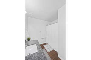 Full bathroom featuring a sink, wood finished floors, baseboards, and a shower with shower curtain