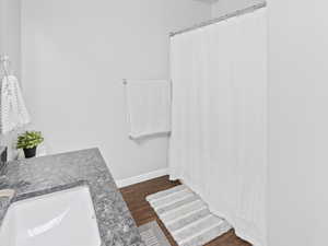 Full bathroom with wood finished floors, baseboards, a shower with curtain, and vanity