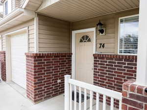 View of exterior entry with brick siding and covered porch
