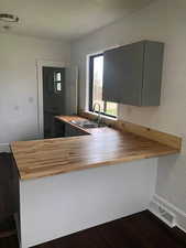 Kitchen with wood counters, a sink, dark wood-style floors, a peninsula, and gray cabinets