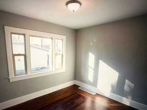 Unit A bedroom 1 healthy amount of natural light dark wood-style floors, baseboards, and a textured wall
