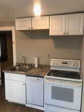 Unit B, Kitchen featuring white appliances, a sink, dark wood-style floors, white cabinetry, and dark countertops