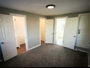 Unit B bedroom featuring dark carpet, baseboards, and ensuite bath