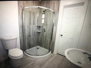 Unit AFull bath with a shower stall, a sink, toilet, and baseboards