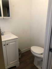 Unit B Bathroom featuring vanity, wood finished floors, toilet, and baseboards