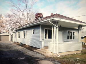 View of property exterior with asphalt driveway, an outdoor structure, a chimney, and a garage