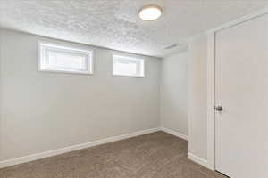 Basement with carpet floors, a textured ceiling, and baseboards