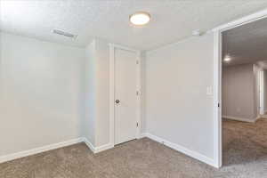 Hallway featuring carpet flooring, a textured ceiling, and baseboards