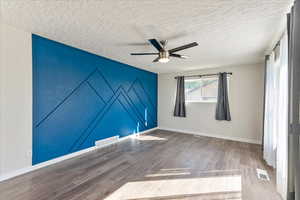 Unfurnished room featuring a textured ceiling, baseboards, a ceiling fan, and wood finished floors