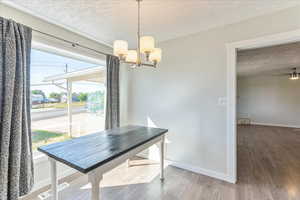 Dining space featuring a textured ceiling, baseboards, a chandelier, wood finished floors, and ceiling fan